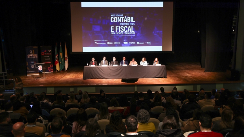 Imagem mostra um público voltado para um palco, onde estão autoridades do evento
