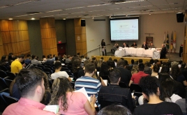 Auditório, pessoas assistindo, mesa principal