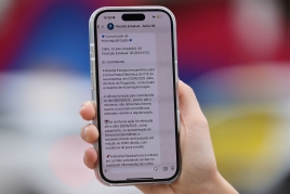 Uma mão segura um celular. Na tela do WhatsApp, há uma mensagem da Receita Estadual sobre um programa de autorregularização
