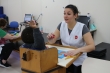 Mulher vestindo uniforme com a inscrição AACD está em frente a uma criança, um menino, que está de costas