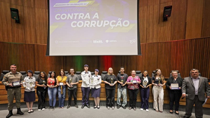 Jovens seguram trof&eacute;us do Escola &Iacute;ntegra. No fundo, na tela, est&aacute; escrito Dia Internacional Contra a Corrup&ccedil;&atilde;o. 