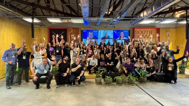 Grupo de mais de 40 pessoas olha para foto e acena.