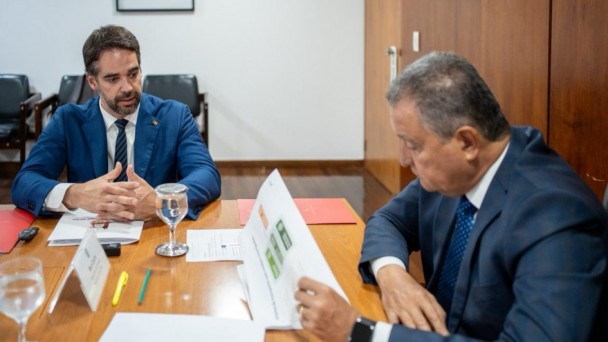 Autoridades reunidas em uma mesa, lendo documentos