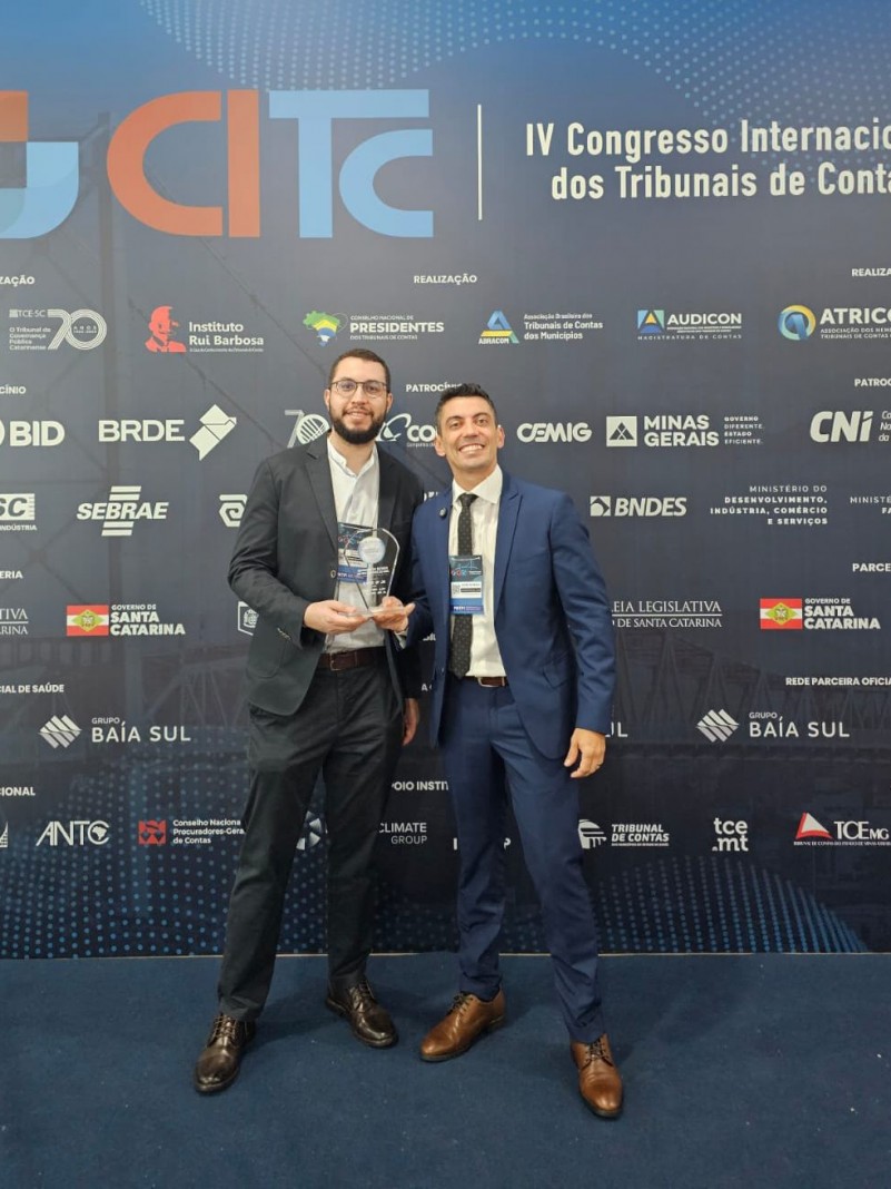 autoridades da CAGE em frente ao painel do evento com a premia&ccedil;&atilde;o em m&atilde;os