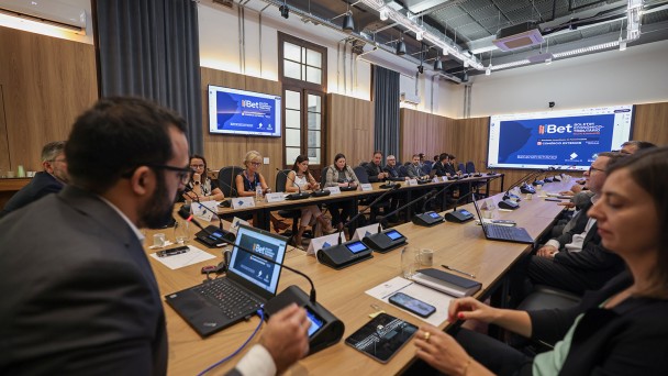 Grupo de pessoas sentando ao redor de uma mesa retangular, sendo um homem falando ao microfone e apresentando o boletim de indicadores de exporta&ccedil;&atilde;o